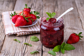 Homemade delicious strawberry jam and strawberry on a rustic wooden table