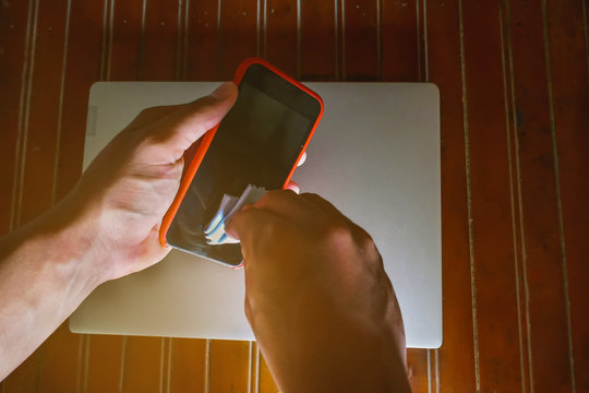 man wiping the surface of his cell phone with a handkerchief - Powered by Adobe