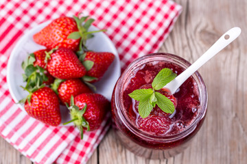 Homemade delicious strawberry jam and strawberry on a rustic wooden table