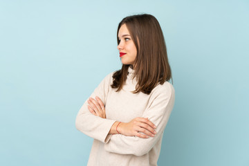 Teenager girl isolated on blue background looking to the side