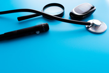 Flat lay composition with glucose meter and stethoscope on light blue background. Space for text