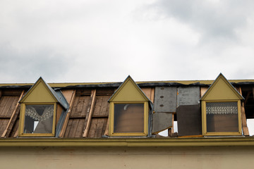 image of an old demolition building with a partially demolished roof and the curtains still in front of the windows