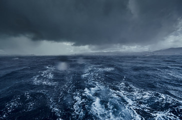 The view of the stormy sea and mountains from the sailboat, Path from foam after the boat, splashes...