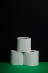The toilet paper roll is green on a black background. Cheap toilet wipes for hygiene purposes. Soft hygienic paper.
