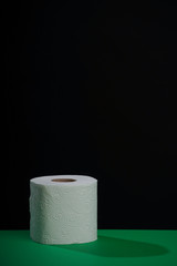 Toilet paper roll. Soft hygienic paper. Black green background.