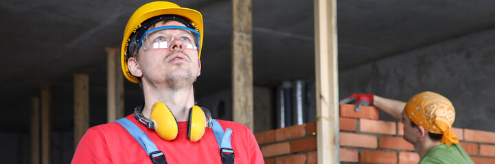 Builder in overalls and helmet makes notes folder