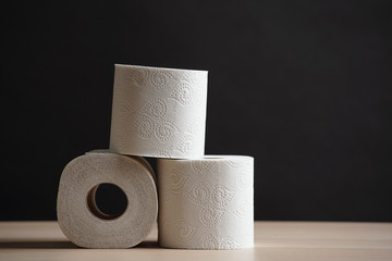 Many toilet paper rolls in a pile. Soft hygienic paper. Wooden table on black background.