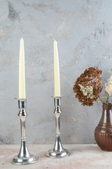 Antique silver candlesticks on concrete background.