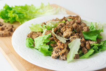 Classic Caesar salad with its ingredients: grilled chicken, croutons, lettuce and dressing sauce