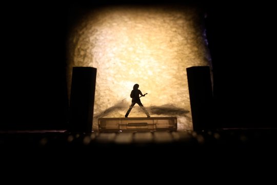 Conceptual Photo, Silhouette Bassist or Guitarist in Action, at Fake Stage, Yellow Lighting
