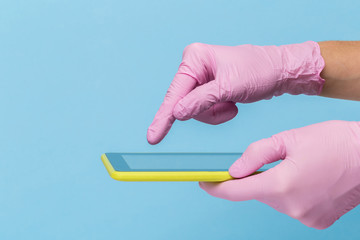 Female hand in a pink medical glove holds a blank modern tablet on a blue background. Mock up, business card, flyer. Technology Concept.