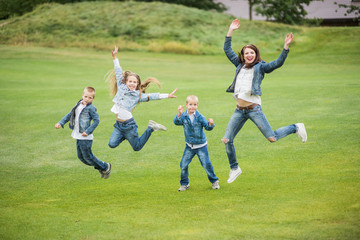 Mother and children on the grass jump