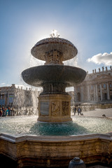 Zabytki na placu Św. Piotra w Watykanie. Na pierwszym planie ogromna fontanna, a w oddali widać bazylikę świętego Piotra, Włochy. - obrazy, fototapety, plakaty