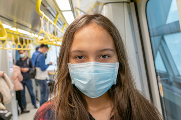 Obraz na płótnie Canvas Young tween girl wearing surgical mask on subway