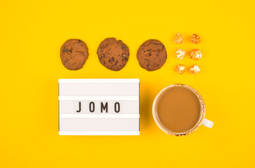 The concept of joy of missing out is written on a bright yellow background.