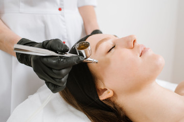 Beautician doing oxygen therapy for young woman laying down with closed eyes in a beauty salon