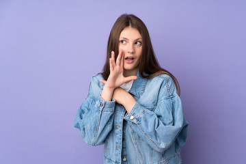 Teenager caucasian girl isolated on purple background pointing to the side to present a product and whispering something