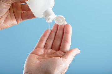 A bottle of Disinfectant gel in your hands on a blue background. Antiseptic treatment of hands from bacteria Sanitizer.