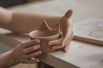 Workflow of a woman working behind a pottery wheel in an art workshop. Unknown master creates a jug. Focus only on the hands. Small business, talent, invention, inspiration concept.