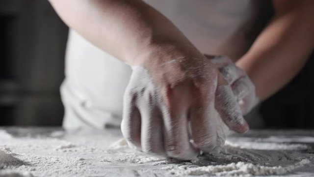 Italian chef in a professional kitchen prepares the dough with flour to make the Italian Pizza.