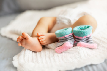 Obraz na płótnie Canvas Newborn baby feet and socks on white blanket, maternity concept