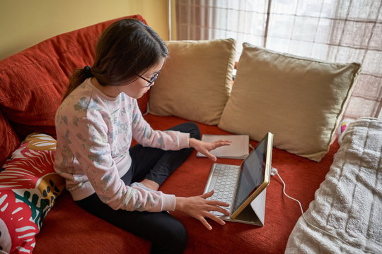 Little girl studying at home with laptop