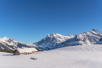 Verschneite Winterlandschaft mit einsamer Berghütte in den Schweizer Bergen