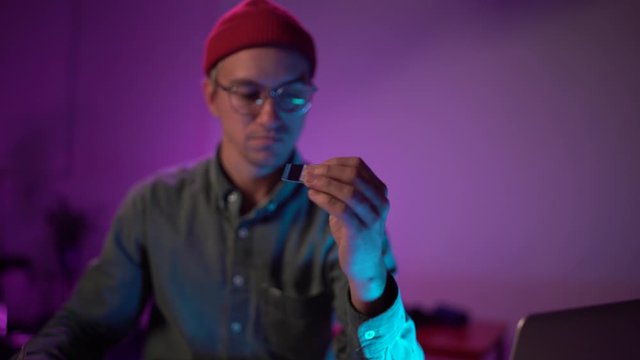 medium shot young man cuts up his credit card. Neon light