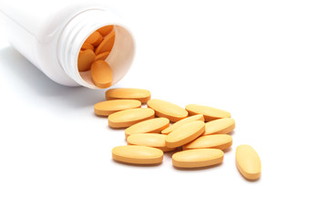 Vitamin C pills spilling out of a drug bottle on white background. For protection Coronavirus (Covid-19)  disease.