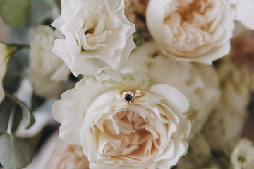 a bouquet of flowers and greenery and a wedding ring