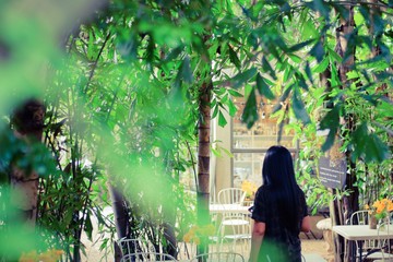 Back view of beautiful young asian woman standing in natural green garden with tree around.