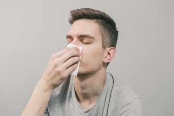 Obraz premium White man gets sick and blows his nose into a white napkin