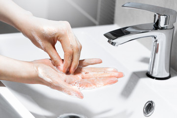 Young woman washing hands with soap under the water tap. Protection for coronavirus. Hygiene concept. 