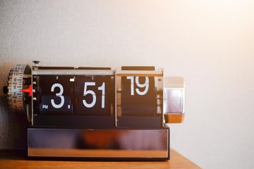 Vintage flip alarm clock on wooden table with light and copy space.