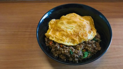 Top view popular food Stir fried pork and chilli basil with omelet on wooden table , Thai delicious yummy food. Copy space for text...