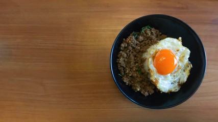 Top view popular food Stir fried pork and chilli basil with fried egg on wooden table , Thai delicious yummy food. Copy space for text...