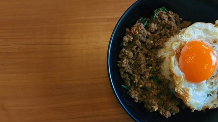 Top view popular food Stir fried pork and chilli basil with fried egg on wooden table , Thai delicious yummy food. Copy space for text...