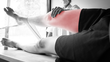 Black and white shot of therapist treating test the strength of the leg muscles of male patient.