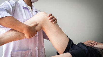 Therapist treating test the strength of the leg muscles of male patient.