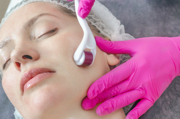 Cosmetologist performs a facial massage using a mesoscooter. Woman at beauty salon during...