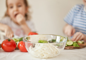 Happy children prepares vegetables for salad in home kitchen. Healthy eating.