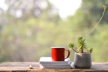 red coffee cup with notebooks and pencil and clay gray plant pot 
