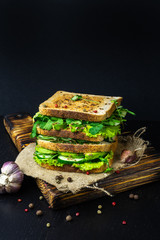 Healthy delicious sandwich with fresh vegetables and prosciutto on the black table
