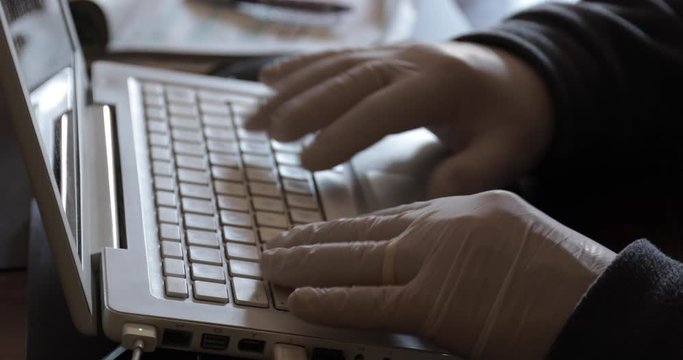 Mani con i guanti che lavorano al computer