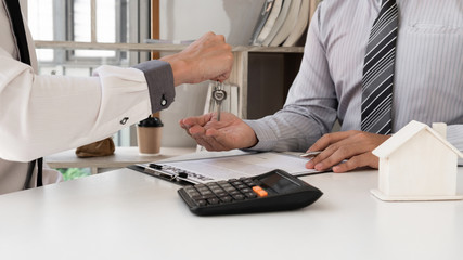 Agent gives a key to customer after finishing an advice for taking the house insurance.