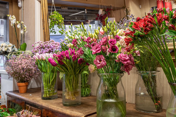 Assortment of beautiful flowers in shop for sale, placed in vases in flower shop. Tulips, roses and limonium.