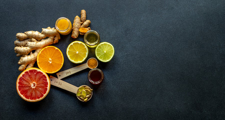 Healthy ingredients for boosting immunity - ginger, turmeric, citruses, and honey on the black...
