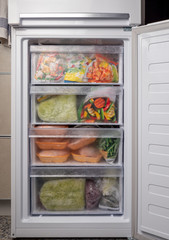 Opened freezer refrigerator with frozen vegetables and meat. Freezed food supplies crisis, food...