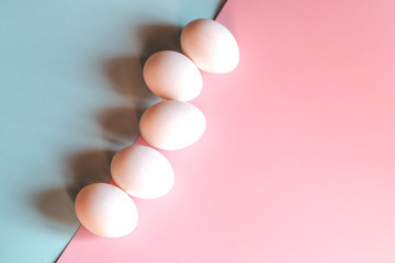 Chicken eggs on a blue and pink background.