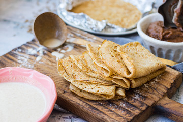 Baked crispy tasty crepes or thin pancakes and crepes dough. Ingredients on table. Vegan dessert. Homemade chocolate paste spread.